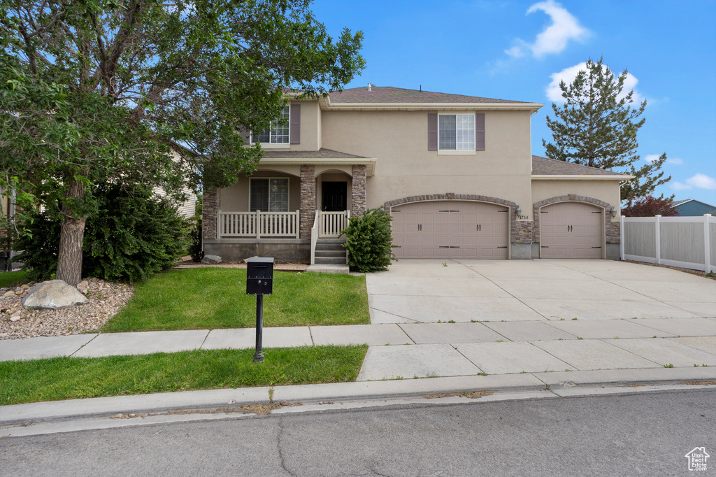 Traditional-style home featuring stucco siding, covered porch, concrete driveway, and a garage