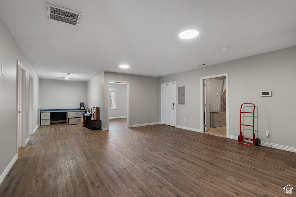 Unfurnished living room with electric panel, dark wood finished floors, and baseboards