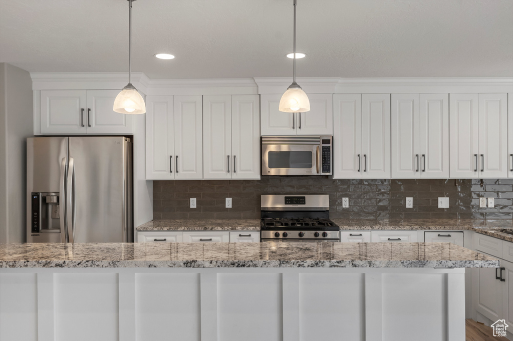 Kitchen with appliances with stainless steel finishes, white cabinetry, hanging light fixtures, and recessed lighting