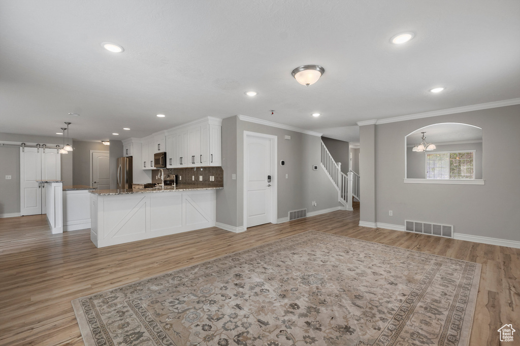Kitchen with white cabinetry, baseboards, a peninsula, ornamental molding, and appliances with stainless steel finishes