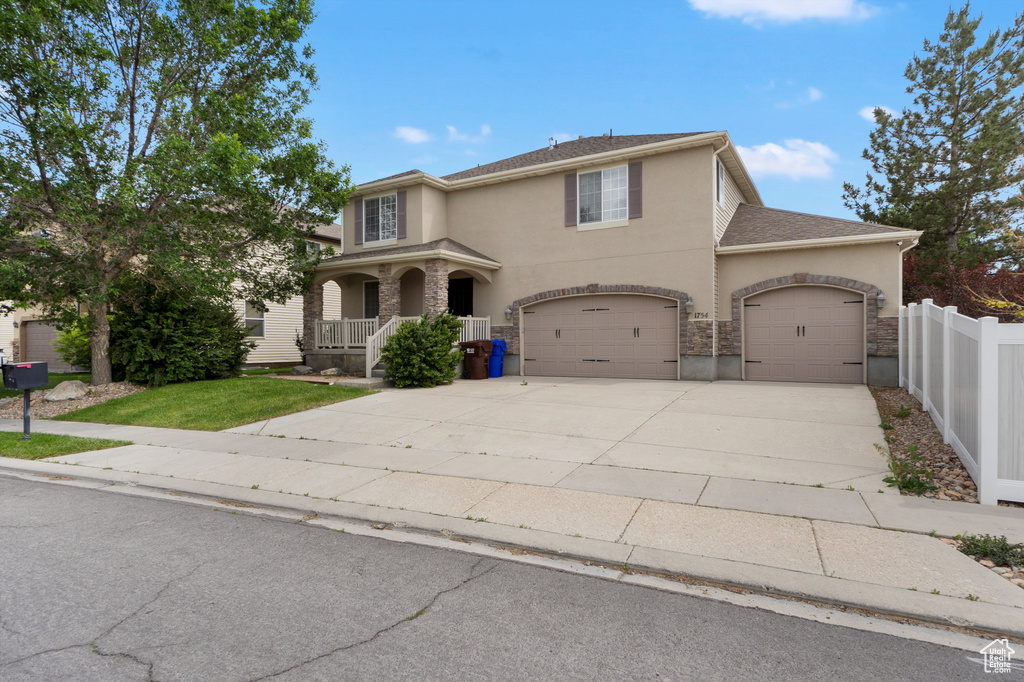 Traditional-style home with stucco siding, concrete driveway, covered porch, a garage, and an attached garage