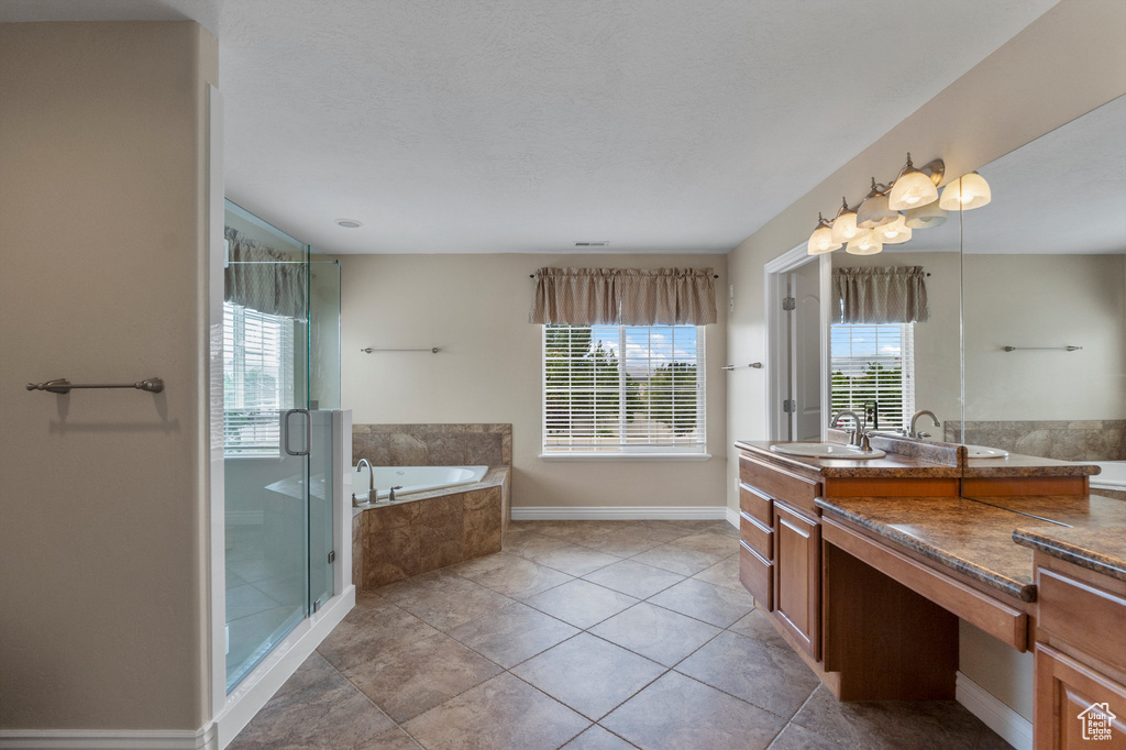 Full bath featuring a garden tub, vanity, a stall shower, baseboards, and tile patterned floors