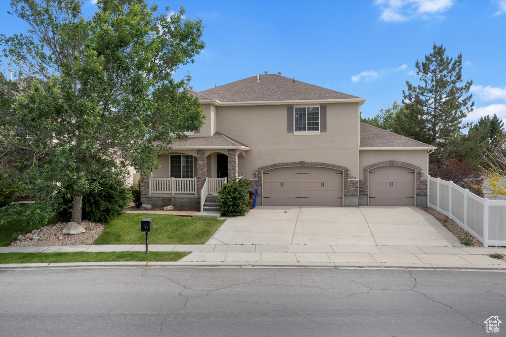 Traditional-style house featuring stucco siding, concrete driveway, covered porch, and a garage