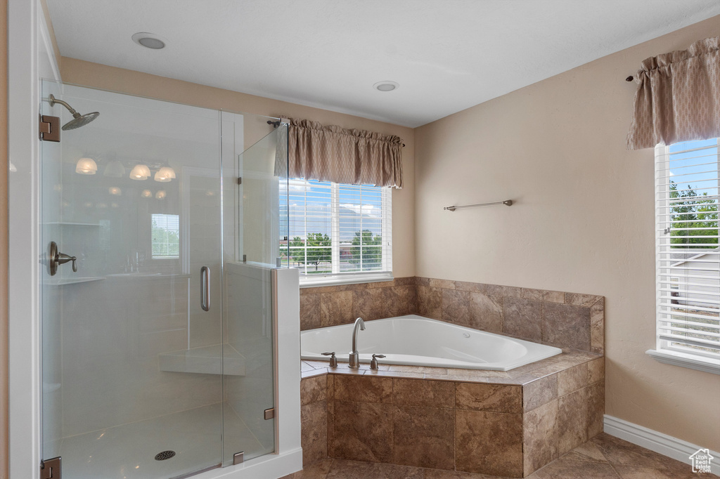 Bathroom with healthy amount of natural light, a shower stall, a garden tub, and tile patterned flooring