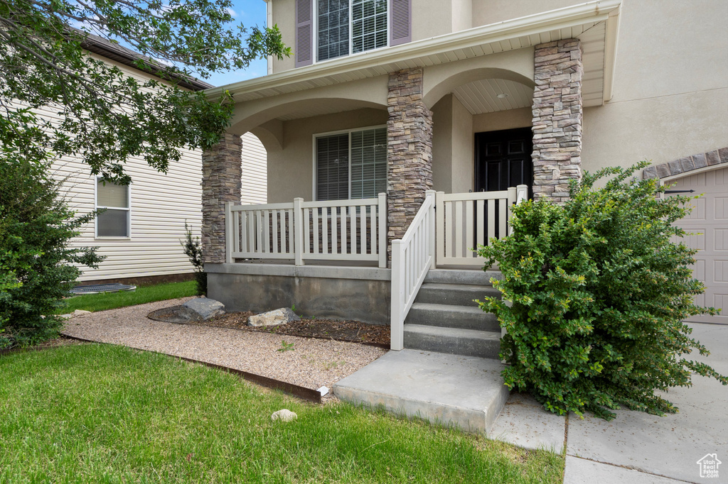 Entrance to property with stucco siding, a porch, and stone siding