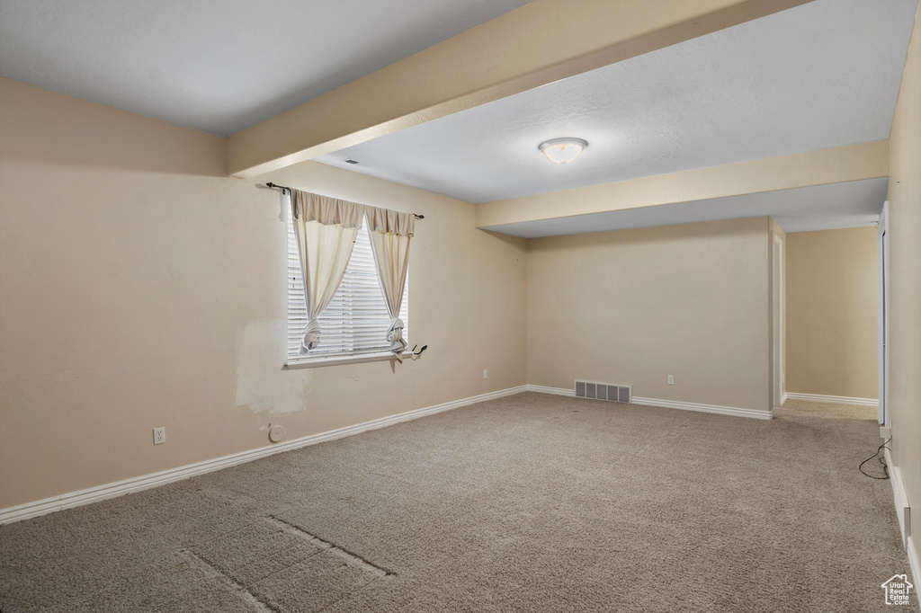 Carpeted spare room featuring baseboards