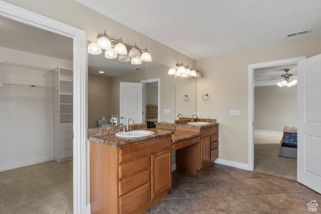Bathroom featuring double vanity, a walk in closet, baseboards, and a ceiling fan