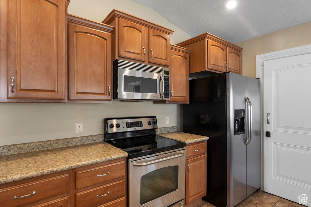 Kitchen with appliances with stainless steel finishes, brown cabinets, and light countertops