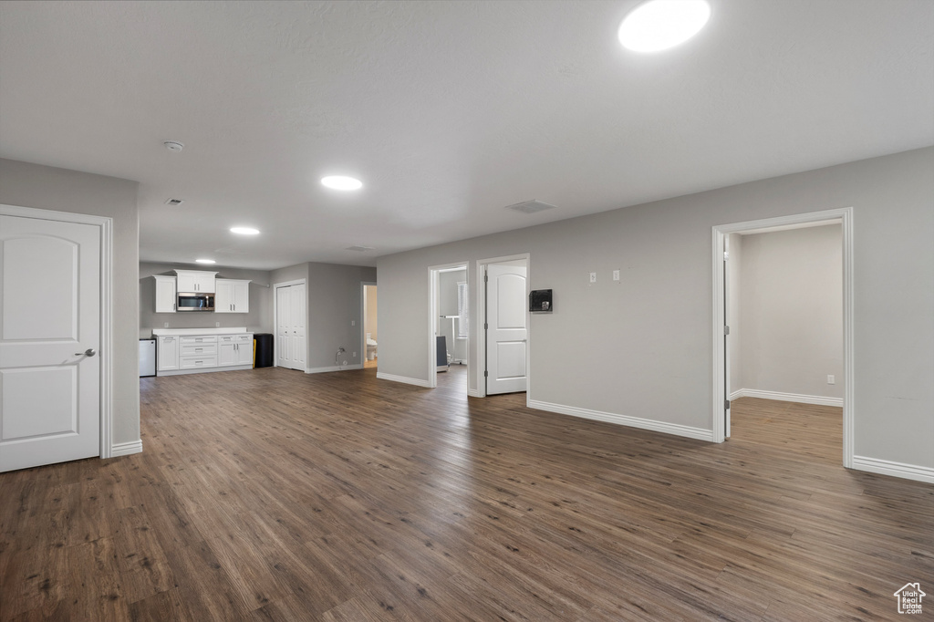 Unfurnished living room with baseboards, dark wood-style floors, and recessed lighting