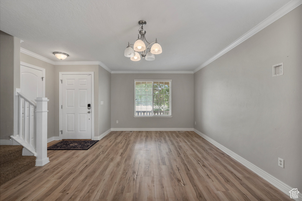 Entryway with stairs, wood finished floors, baseboards, a chandelier, and ornamental molding