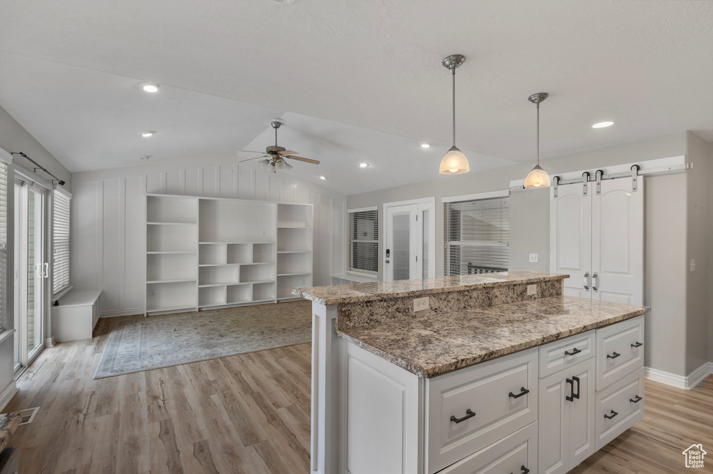 Kitchen with light wood-type flooring, a ceiling fan, open floor plan, lofted ceiling, and white cabinets