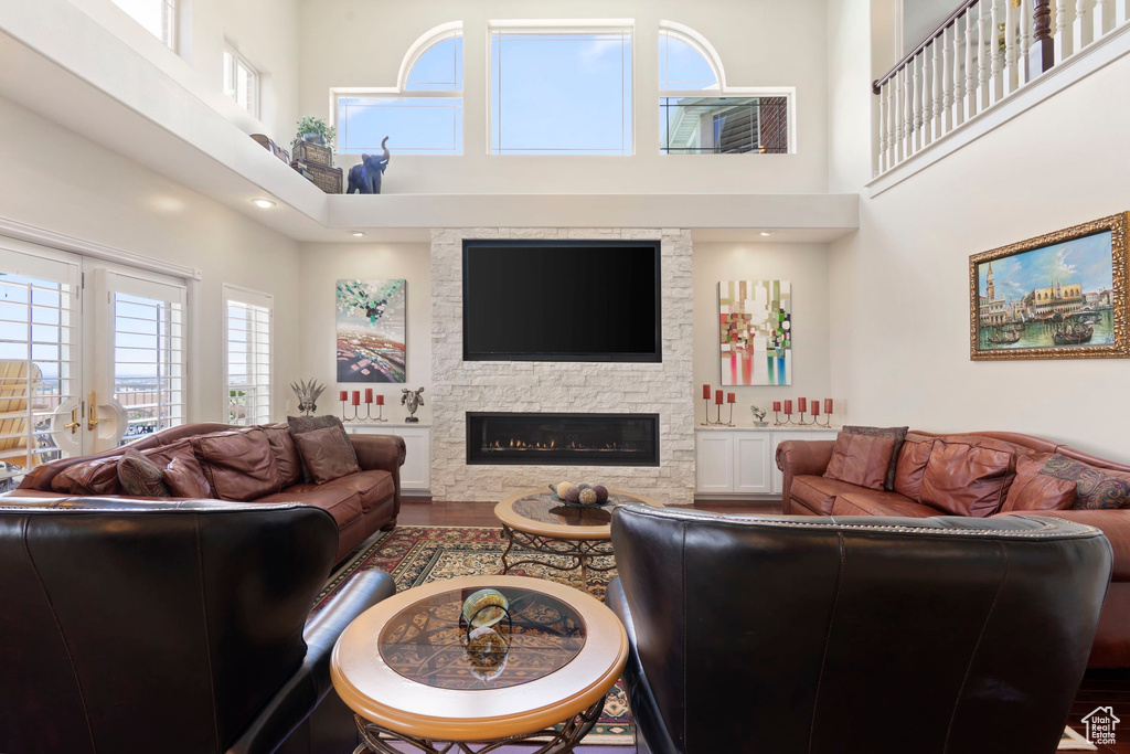 Living room featuring a high ceiling, a fireplace, and wood finished floors