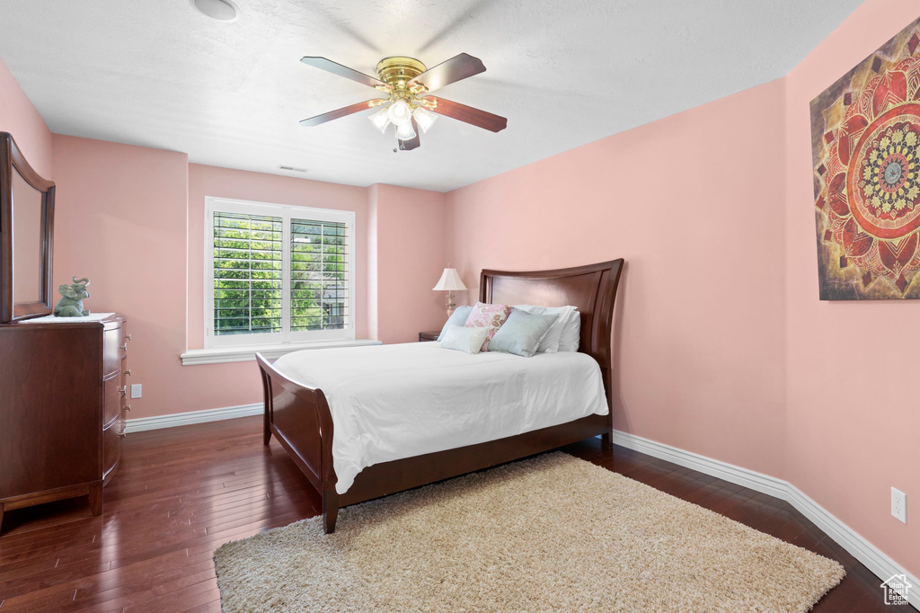 Bedroom featuring dark wood finished floors, baseboards, and ceiling fan