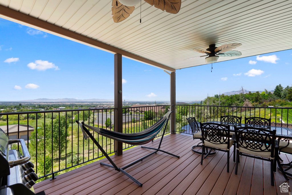 Deck with a ceiling fan, a mountain view, and outdoor dining area