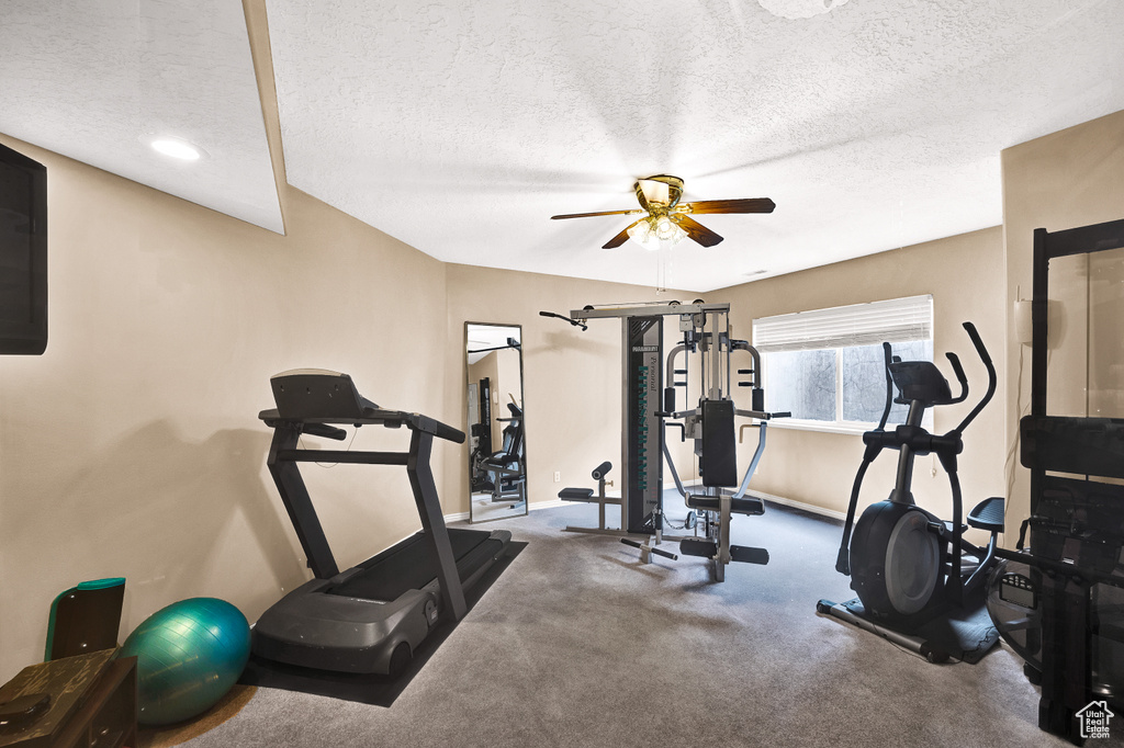 Exercise area with a textured ceiling, ceiling fan, and baseboards