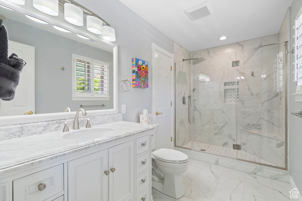 Bathroom with a marble finish shower, toilet, vanity, marble look tile flooring, and recessed lighting