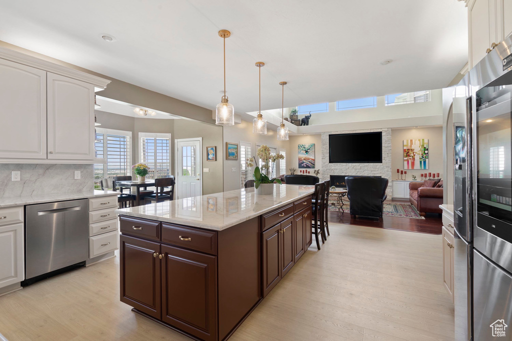 Kitchen featuring appliances with stainless steel finishes, light wood finished floors, dark brown cabinets, and white cabinetry