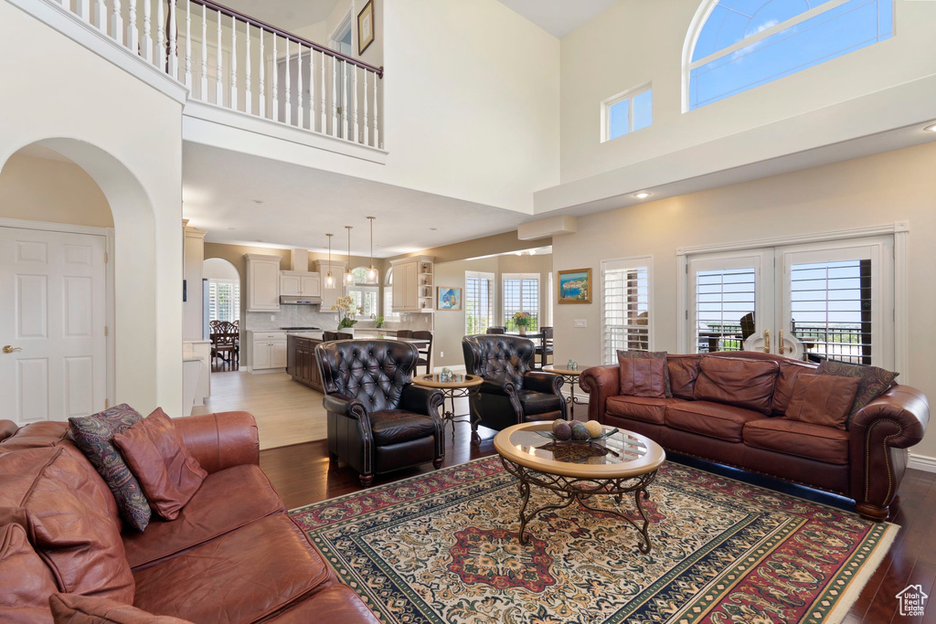 Living area featuring hardwood / wood-style flooring, healthy amount of natural light, a high ceiling, and arched walkways