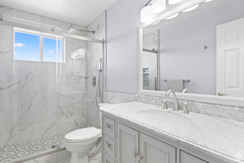 Bathroom with marble finish floors, toilet, vanity, and a marble finish shower