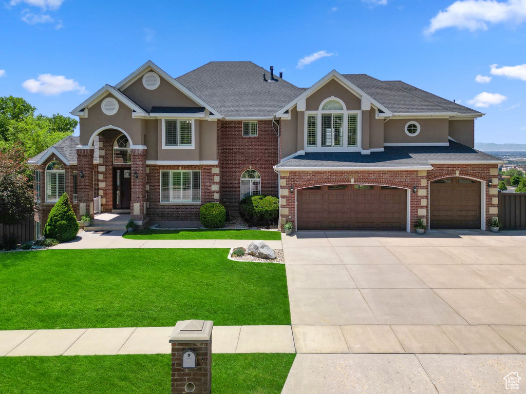 Traditional home featuring a garage, a front lawn, concrete driveway, and stucco siding