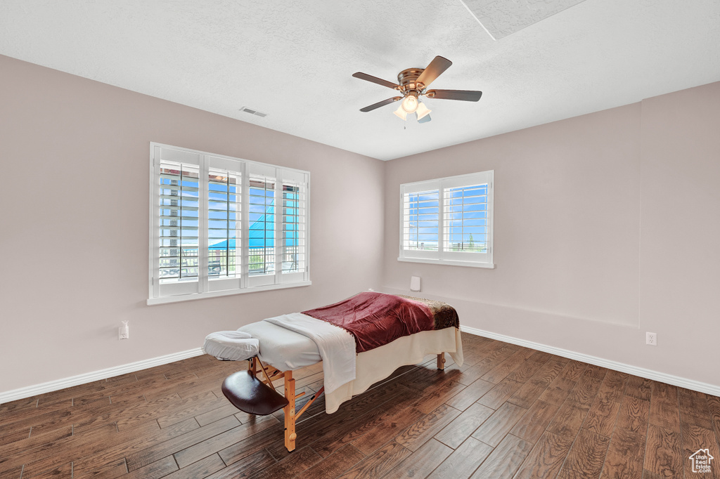Bedroom with wood finished floors, baseboards, ceiling fan, and a textured ceiling