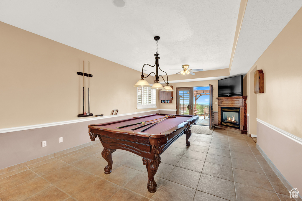 Recreation room featuring ceiling fan, tile patterned flooring, a multi sided fireplace, and billiards