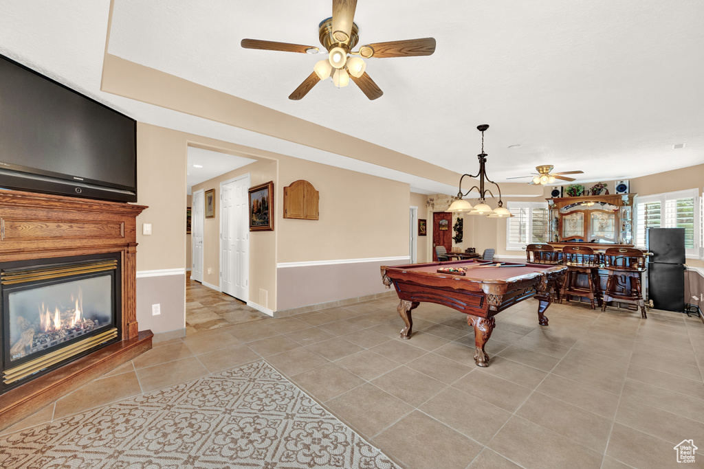 Rec room featuring ceiling fan, billiards table, a glass covered fireplace, and light tile patterned floors