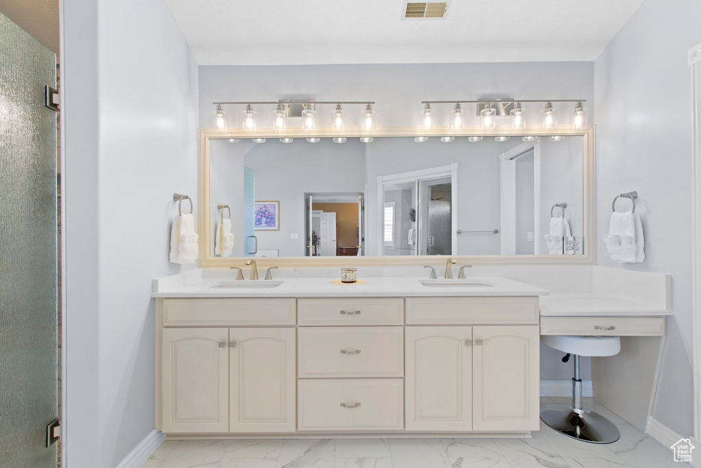 Full bathroom featuring marble look tiles, baseboards, double vanity, and a shower stall