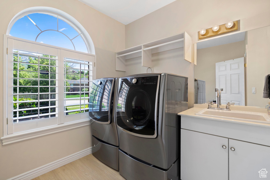 Washroom featuring washer and dryer, light wood-style flooring, and baseboards