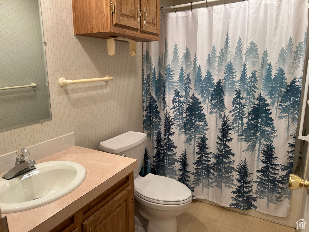 Bathroom with vanity, toilet, wallpapered walls, and curtained shower