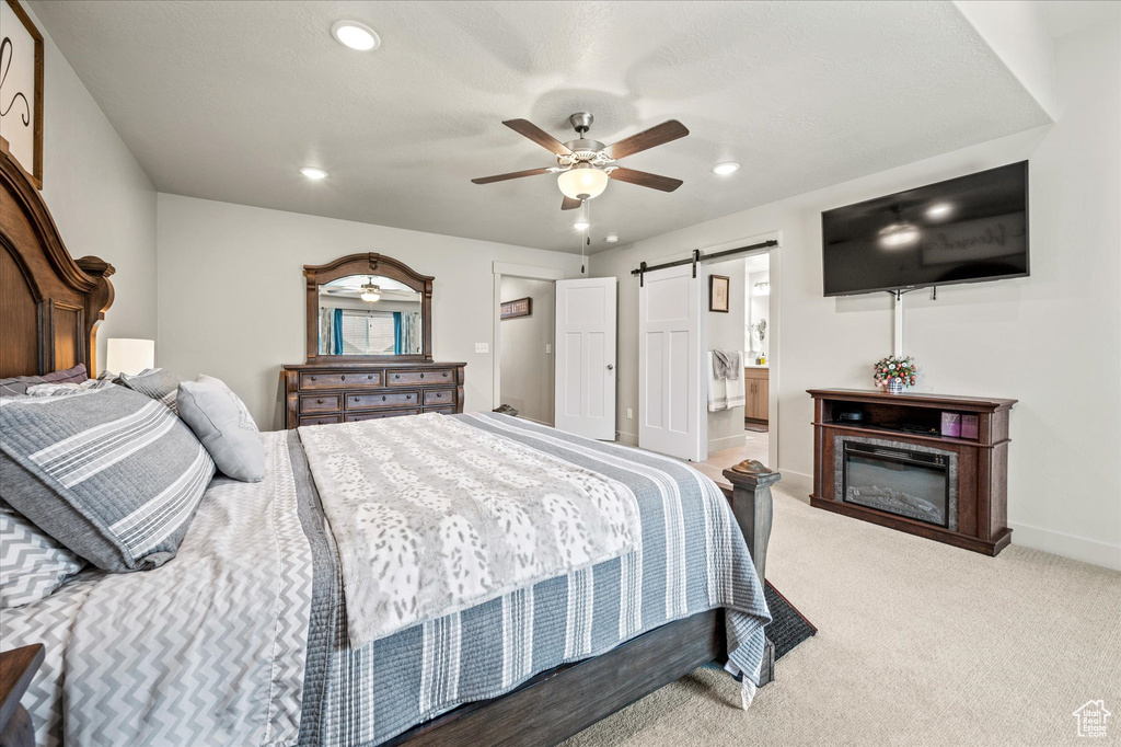 Bedroom featuring a barn door, recessed lighting, baseboards, light carpet, and a ceiling fan