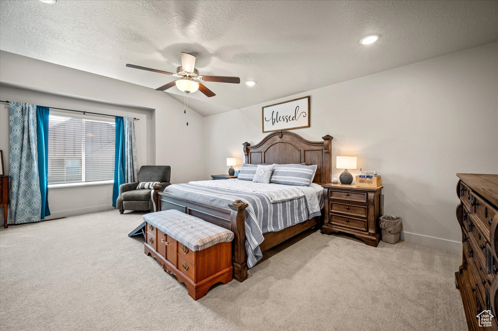 Bedroom featuring carpet floors, baseboards, vaulted ceiling, a textured ceiling, and ceiling fan