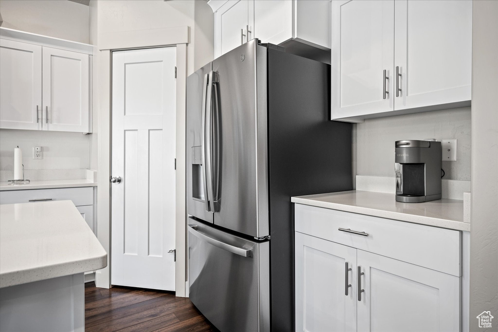 Kitchen featuring stainless steel refrigerator with ice dispenser, light countertops, white cabinets, and dark wood-style flooring