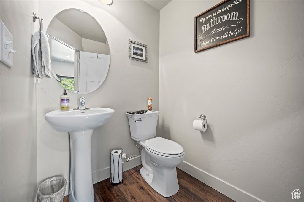Half bath with wood finished floors, toilet, and baseboards