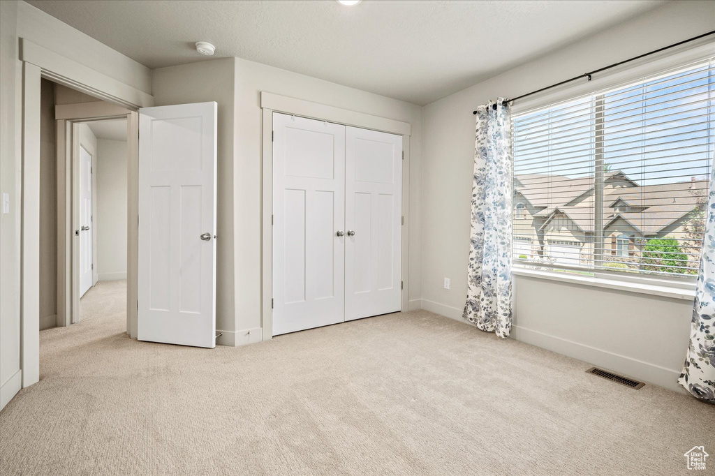 Unfurnished bedroom featuring carpet, multiple windows, baseboards, and a closet
