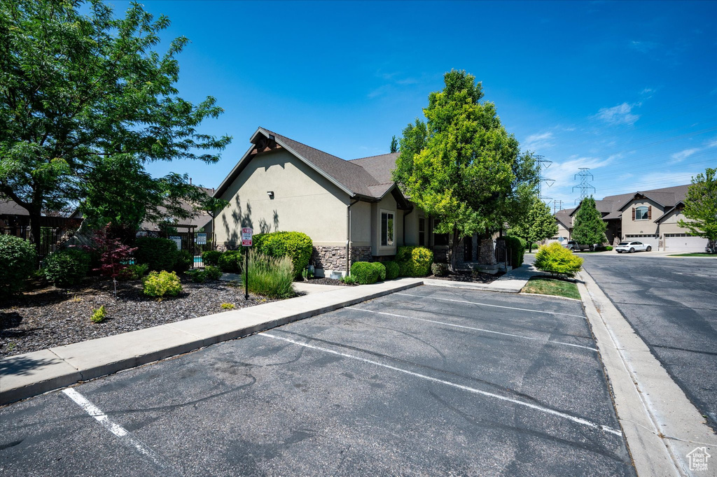 View of front of home with uncovered parking, stone siding, and stucco siding