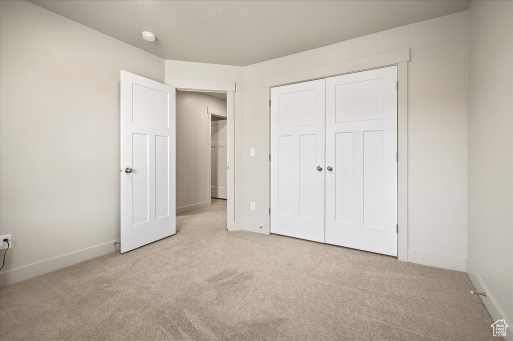 Unfurnished bedroom with carpet floors, baseboards, and a closet