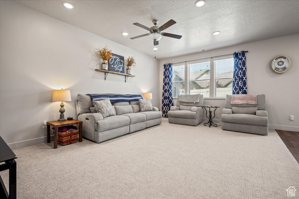 Carpeted living area featuring a ceiling fan, baseboards, a textured ceiling, and recessed lighting