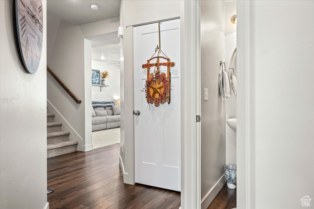 Foyer featuring dark wood-style flooring, baseboards, and stairway