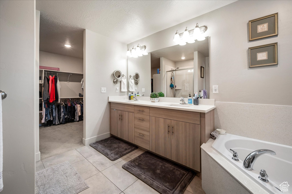 Bathroom with a shower stall, tile patterned flooring, double vanity, a garden tub, and a walk in closet