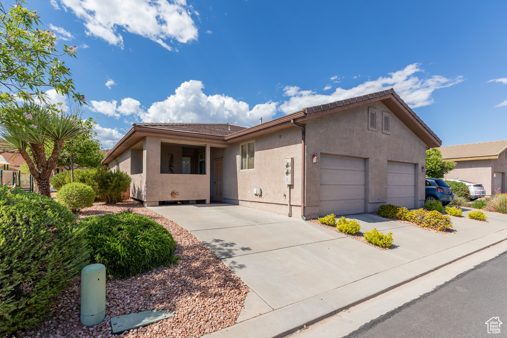 Ranch-style house featuring stucco siding, a garage, and driveway