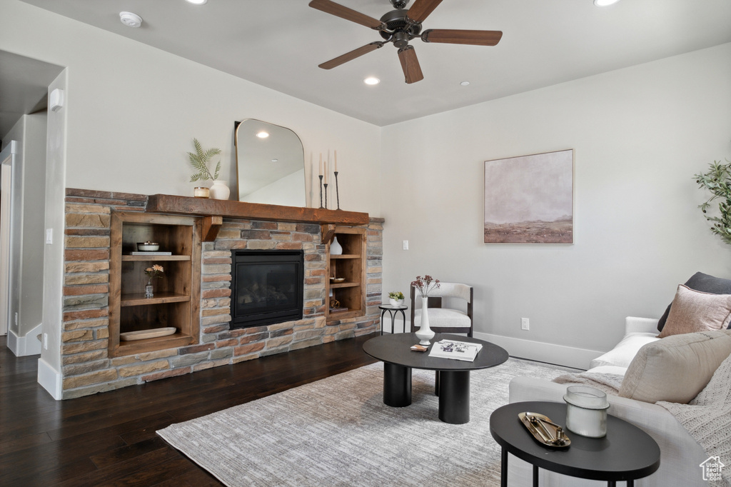 Living room with ceiling fan, a stone fireplace, recessed lighting, wood-type flooring, and baseboards