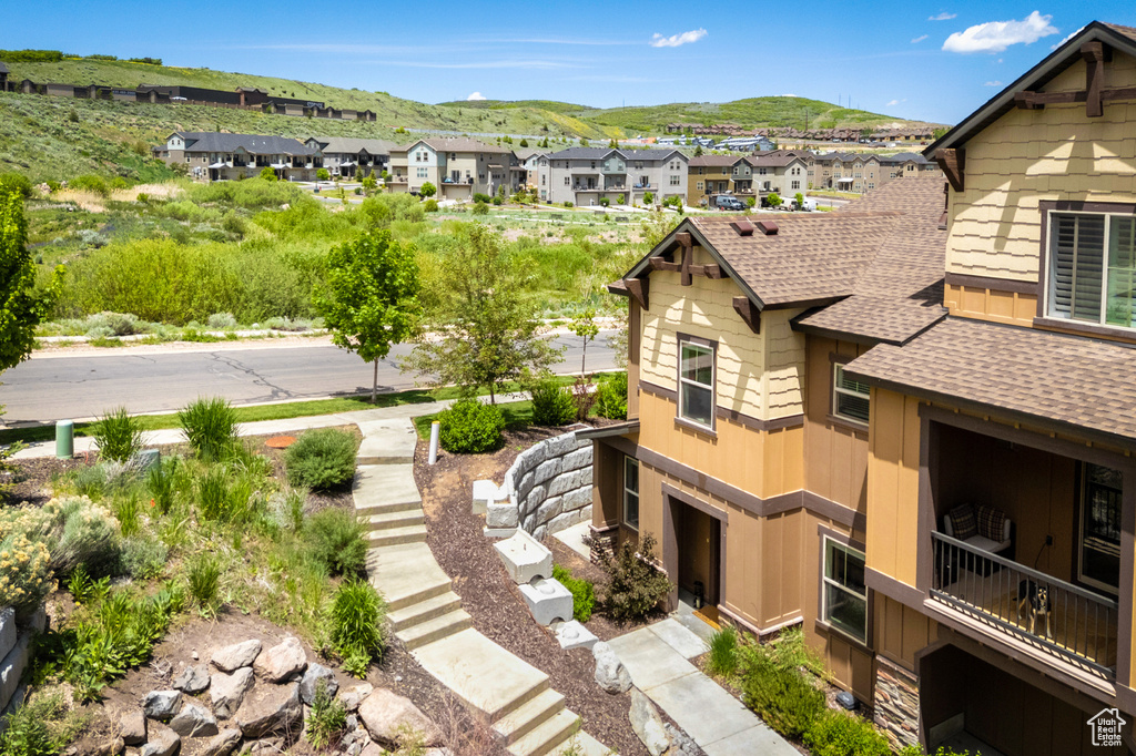 View of side of home featuring a shingled roof, a residential view, and a mountain view