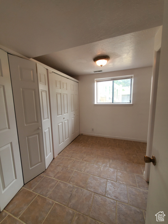 Unfurnished bedroom featuring baseboards, stone finish flooring, and a closet