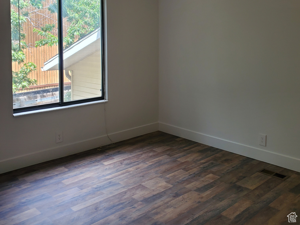 Unfurnished room featuring dark wood finished floors, baseboards, and ceiling fan