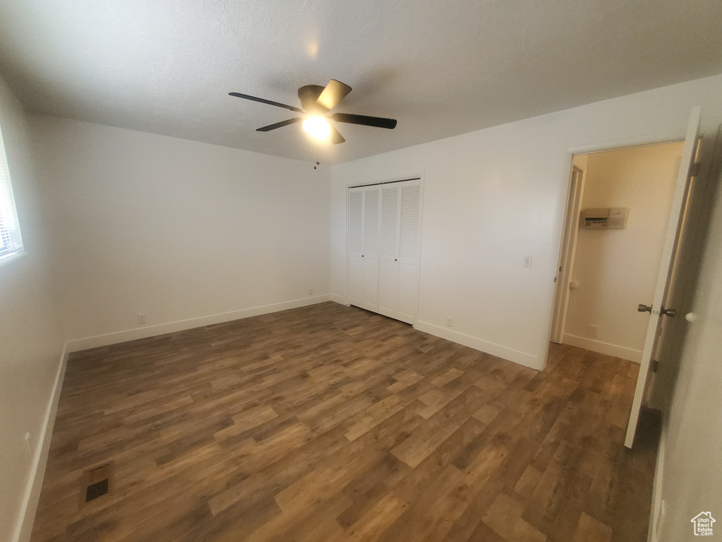 Unfurnished bedroom with wood finished floors, baseboards, a closet, and a ceiling fan