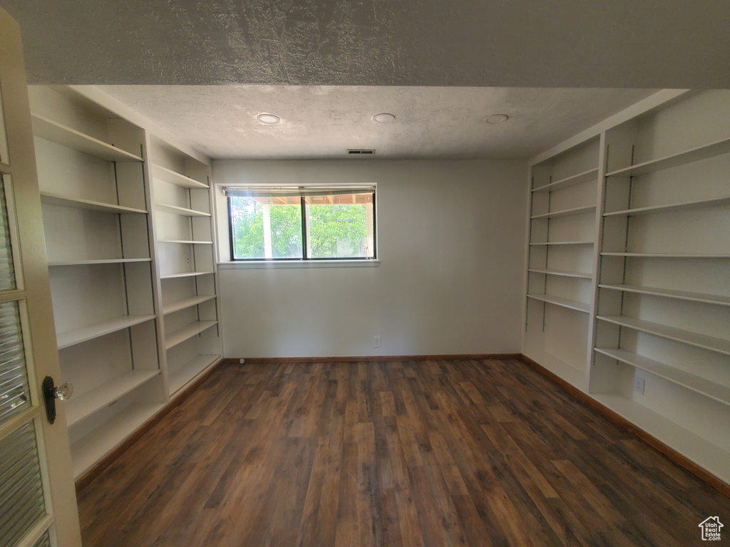 Spare room with baseboards, dark wood finished floors, built in shelves, a textured ceiling, and recessed lighting