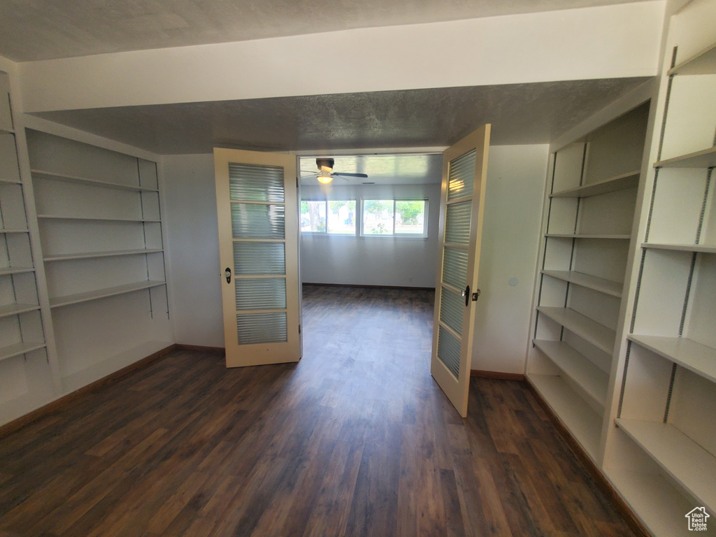 Unfurnished dining area with built in features, dark wood finished floors, baseboards, and a ceiling fan