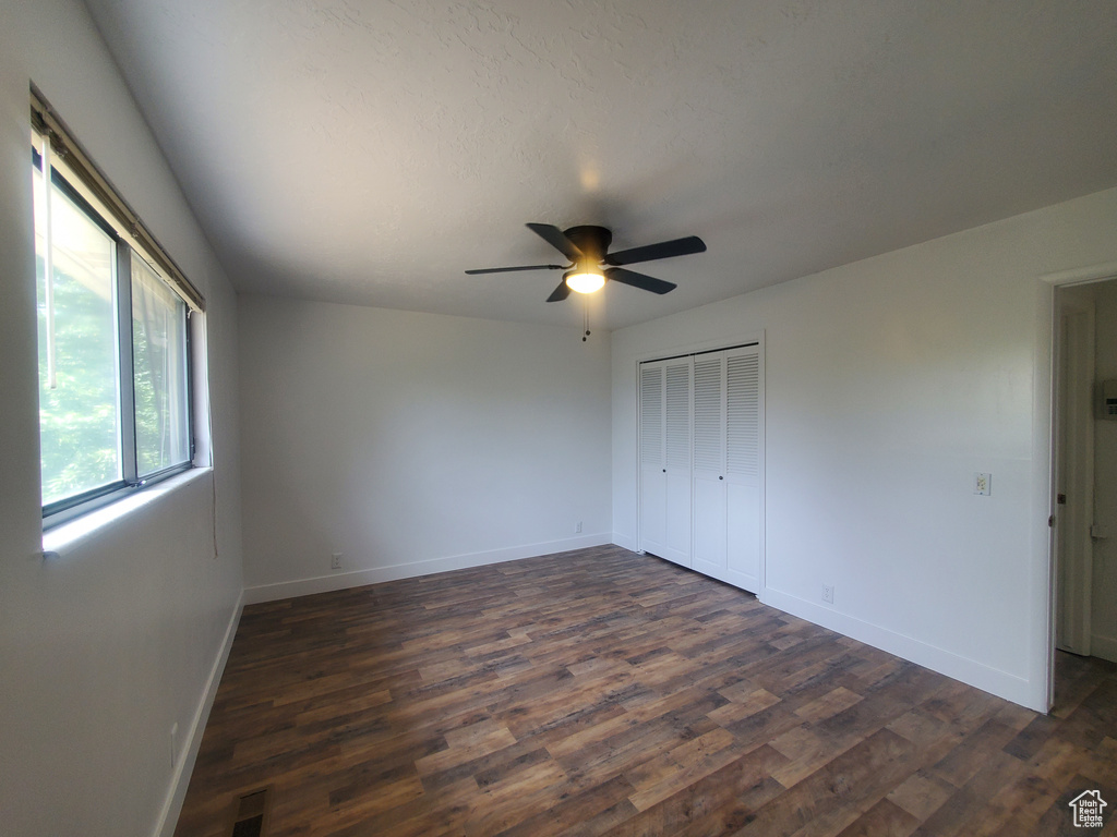 Unfurnished bedroom with dark wood-style floors, baseboards, a closet, and ceiling fan