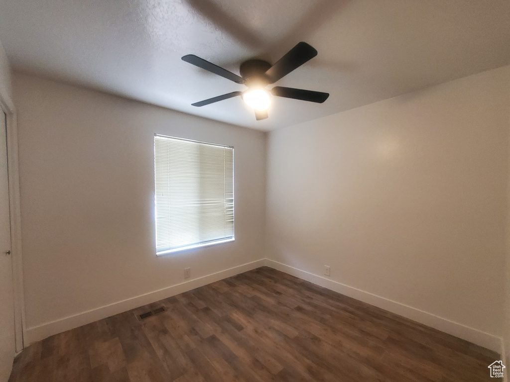 Unfurnished room featuring ceiling fan, dark wood-style floors, and baseboards